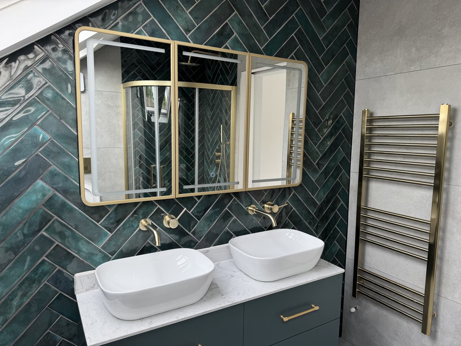 Recently completed loft bathroom — twin vessel basins, green herringbone tile, brushed brass.