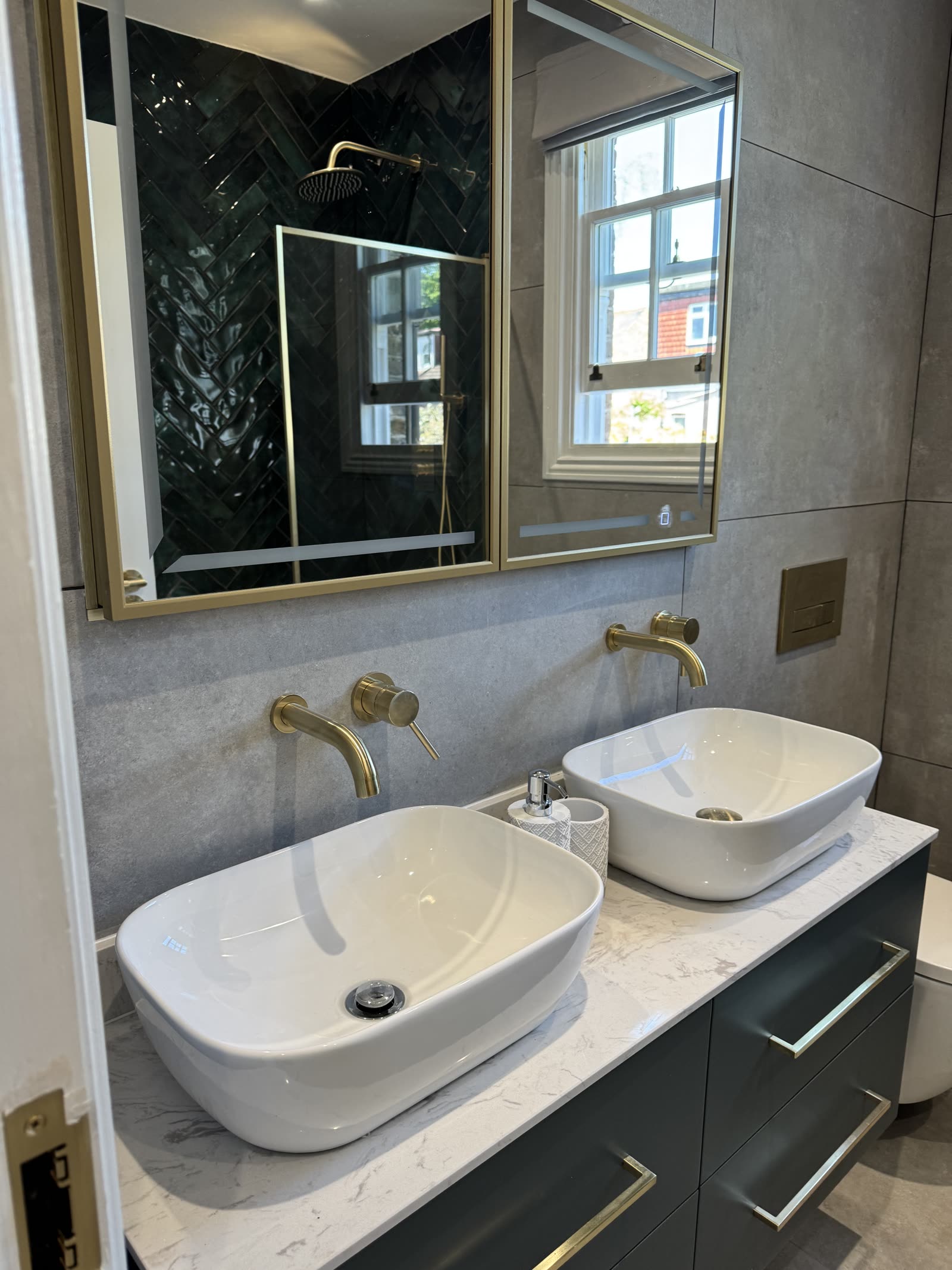 Bathroom with twin vessel basins, marble waterfall splashback and brushed brass taps.