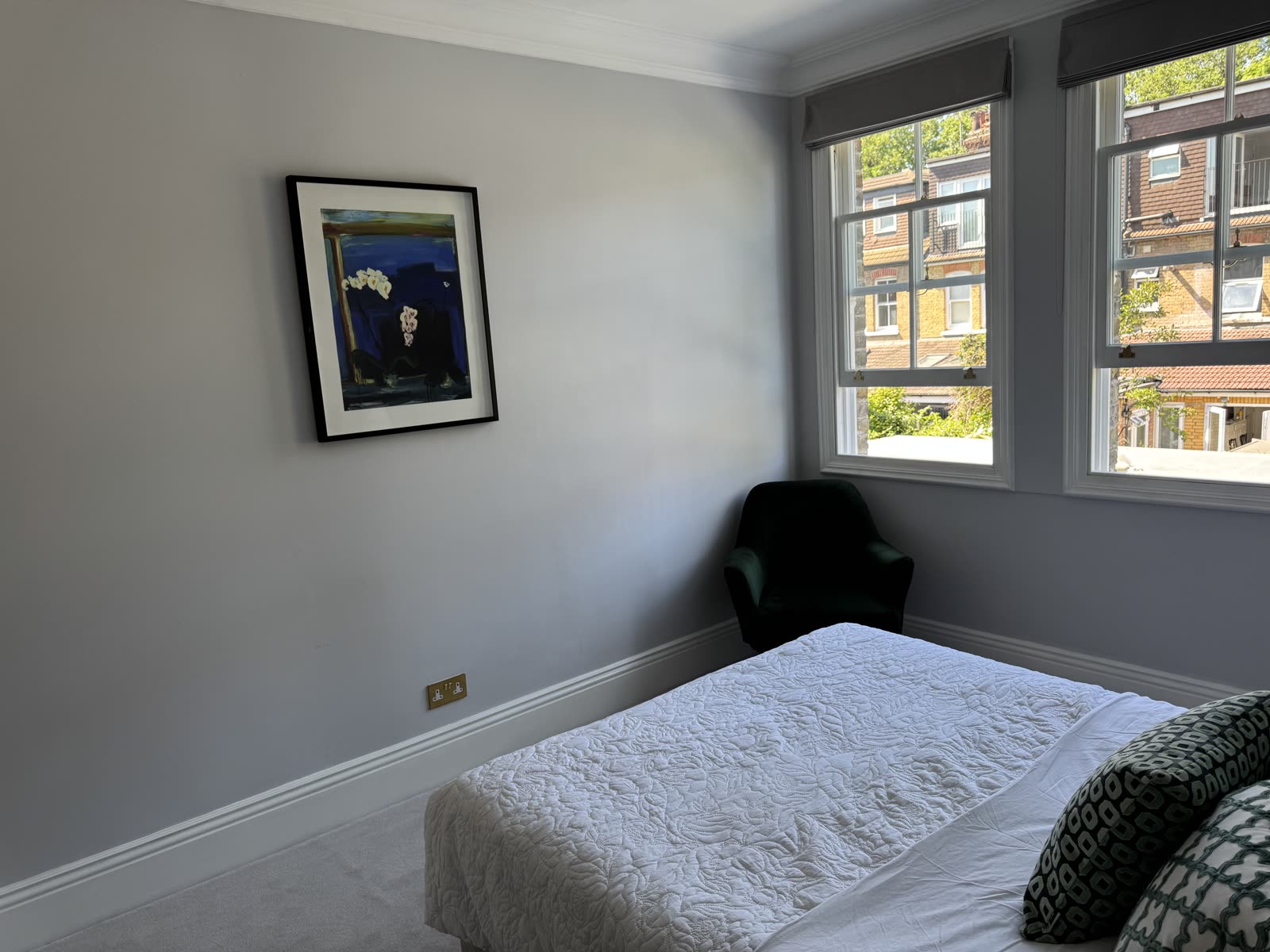 Neutral bedroom with coved ceiling, sash windows and framed artwork.