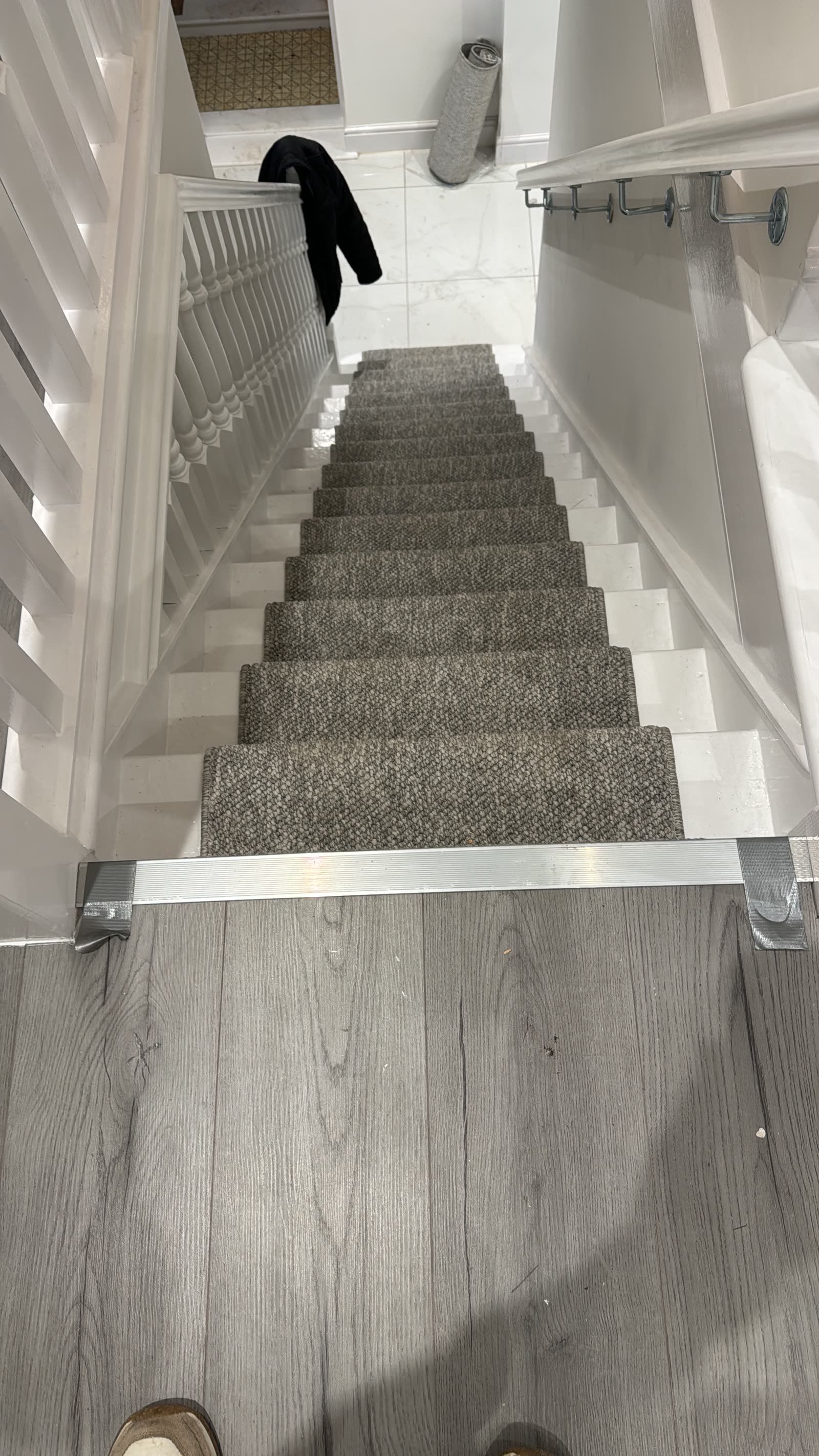 Grey loop-pile stair runner on white painted stairs with contemporary metal balustrade.