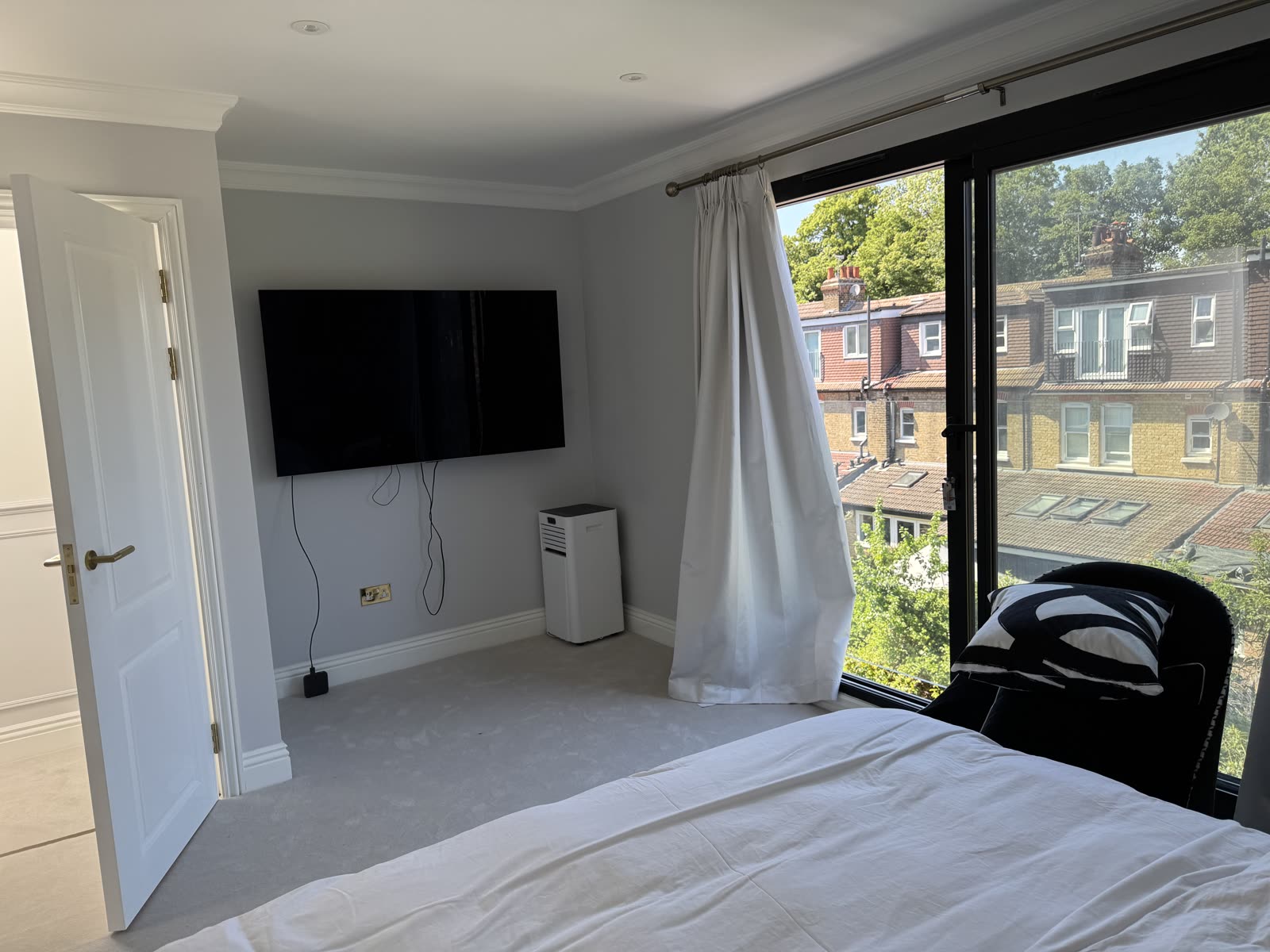 Bedroom with floor-to-ceiling sliding doors opening onto a balcony with rooftop views.