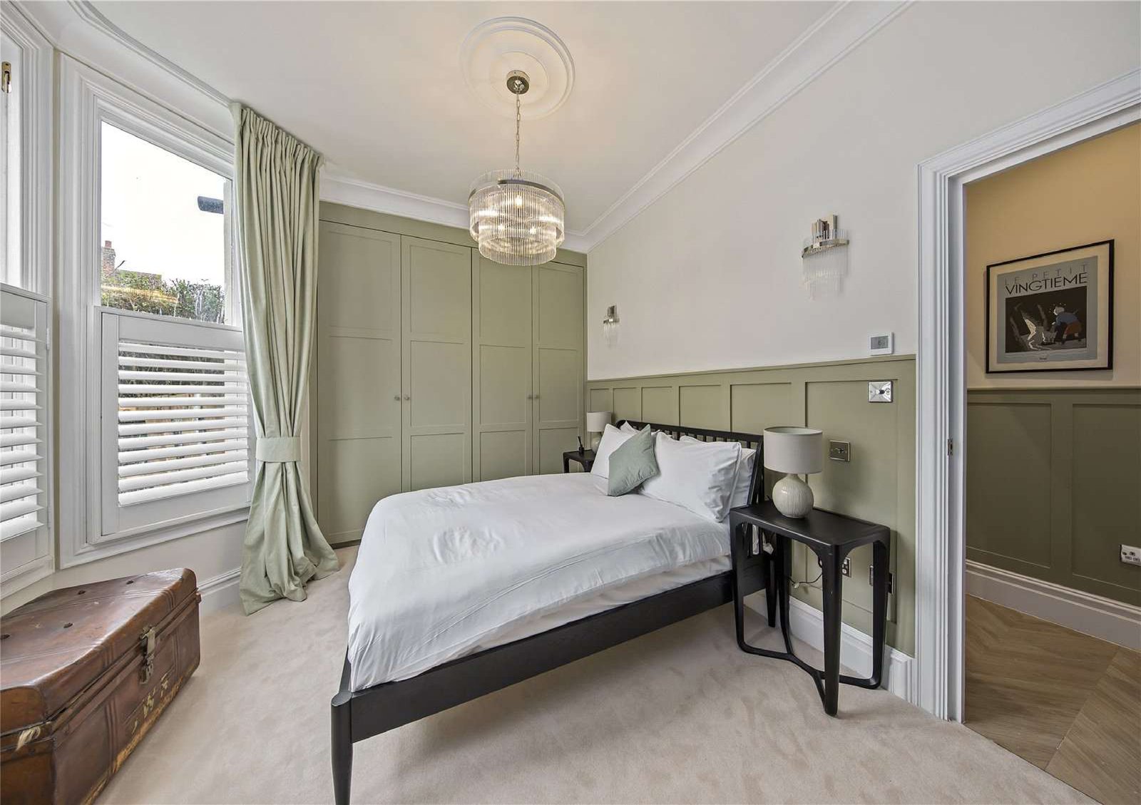 Second bedroom with sage-green panelled walls and white plantation shutters — Flat 1.