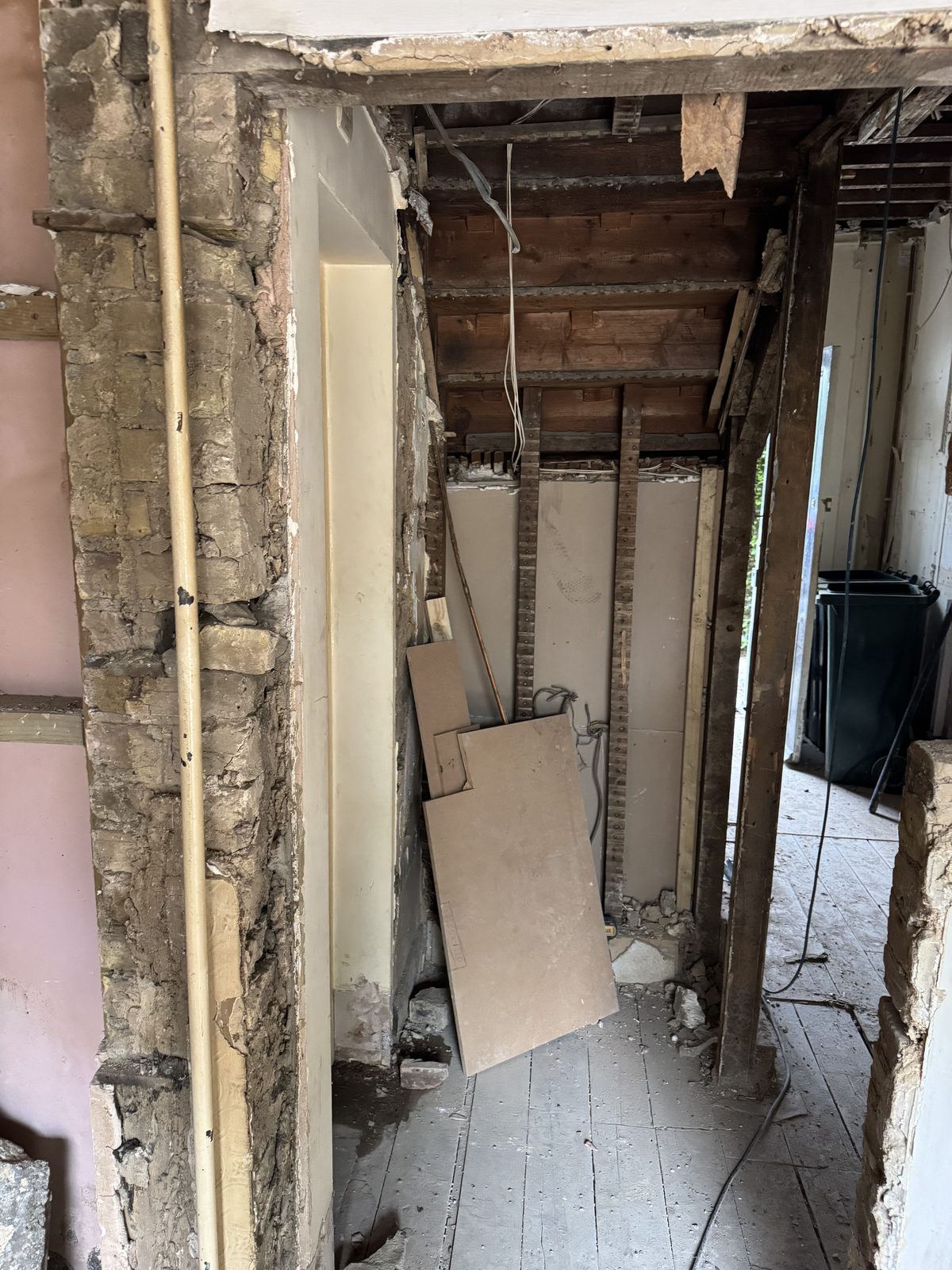 Reception room stripped back to bare brick and timber joists — before.