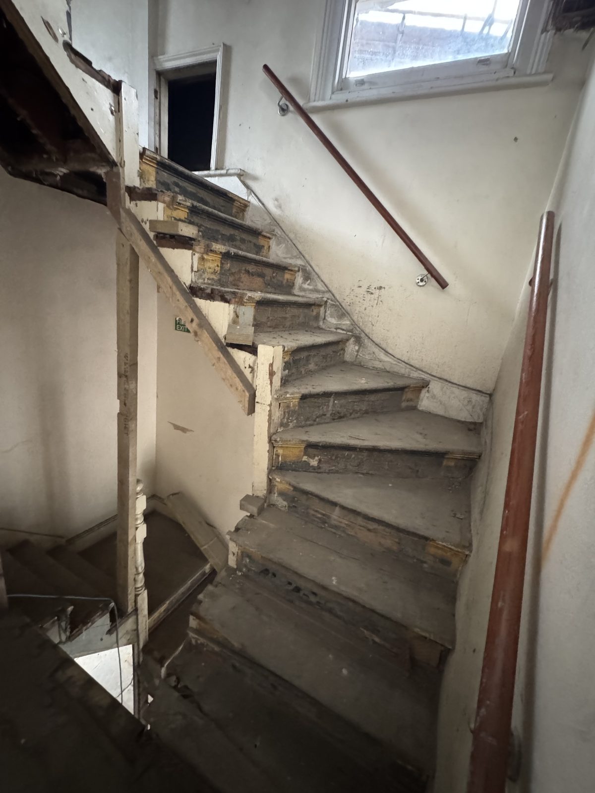 Stairwell and upper floor stripped back to structure beneath a new rooflight opening — before.