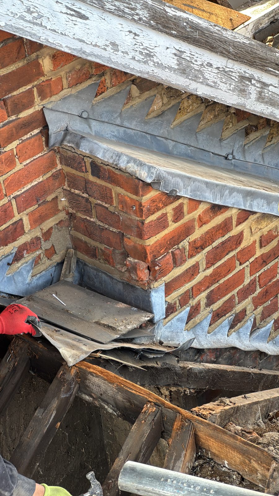 Original roof timbers and brick chimney exposed, showing the condition before rebuilding — before.