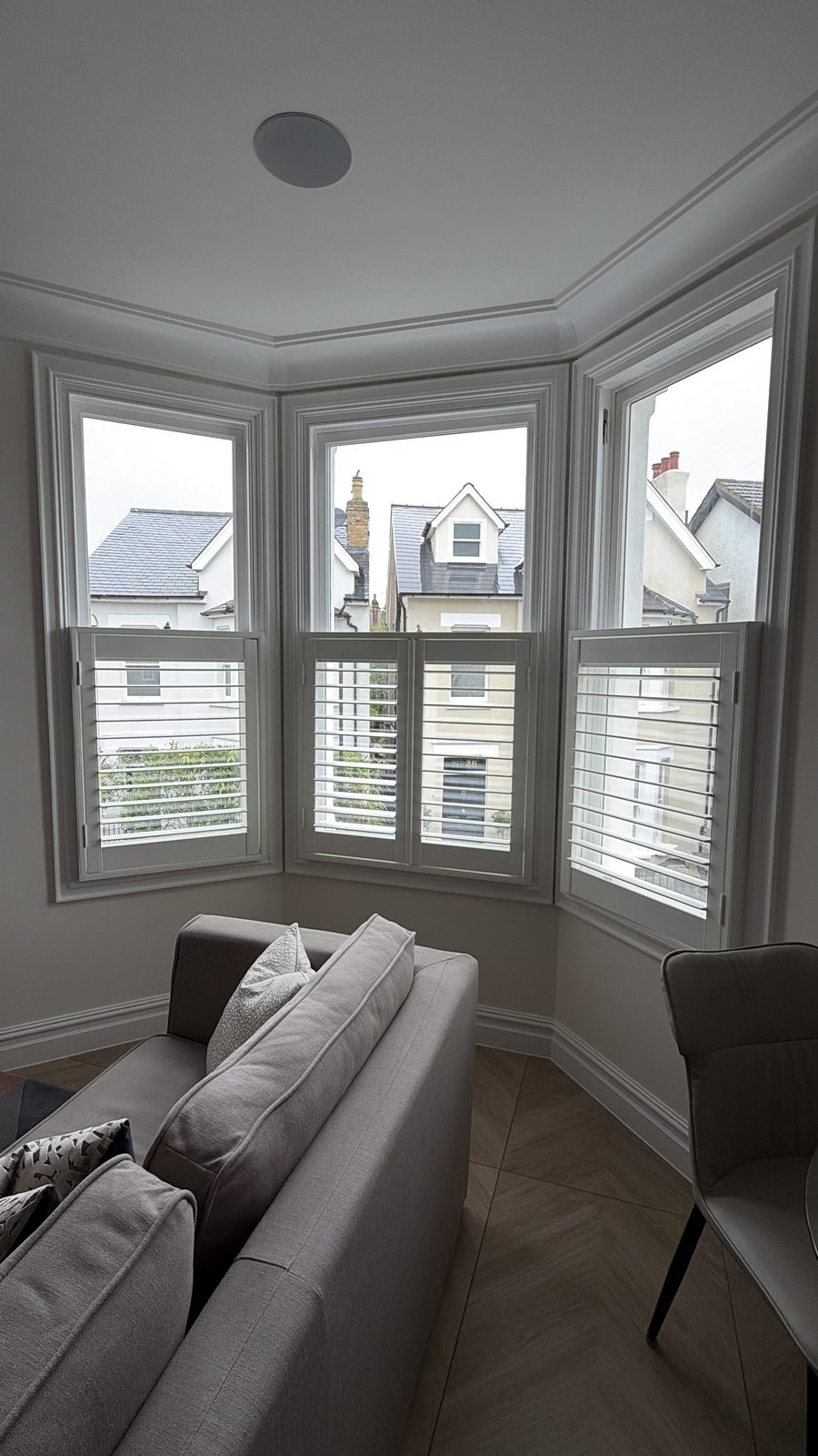 Living room set in a bay window with plantation shutters, grey sofas and herringbone floor — Flat 2.