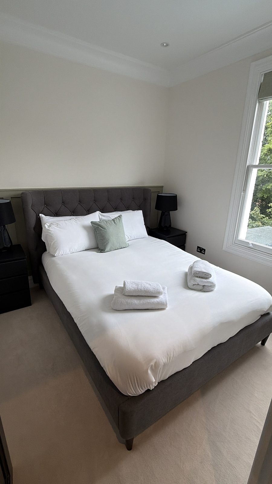 Bedroom with upholstered bed and large sash window — Flat 2.